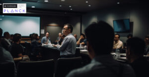 Photo of someone speaking in a meeting. Firemark and Planck logos in top left corner.