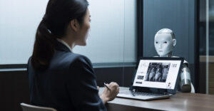 Photo of Japanese person looking at computer with robot/AI behind computer.