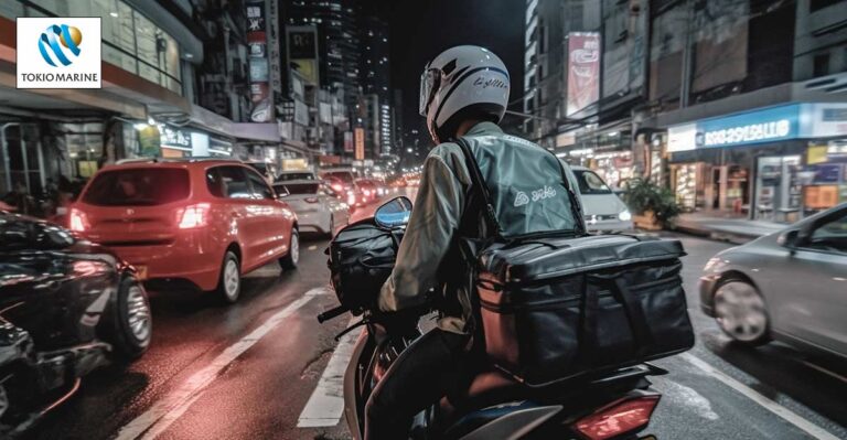 Photo of gig worker motorcyclist drinking through streets of Malaysia. Tokio Marine logo in top left corner.