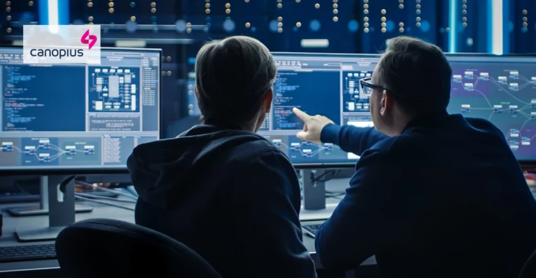 A photo of programmers looking at a blockchain. Canopius logo in top left corner.