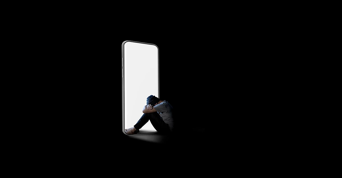 A photo of a dark room with someone in head in hands in the light of a doorway that looks like a phone.