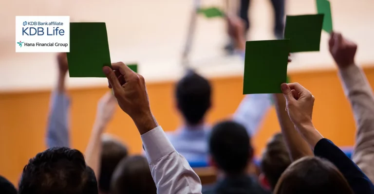 A photo of people holding up bid cards. Hana Financial and KDB Life logos in top left corner.