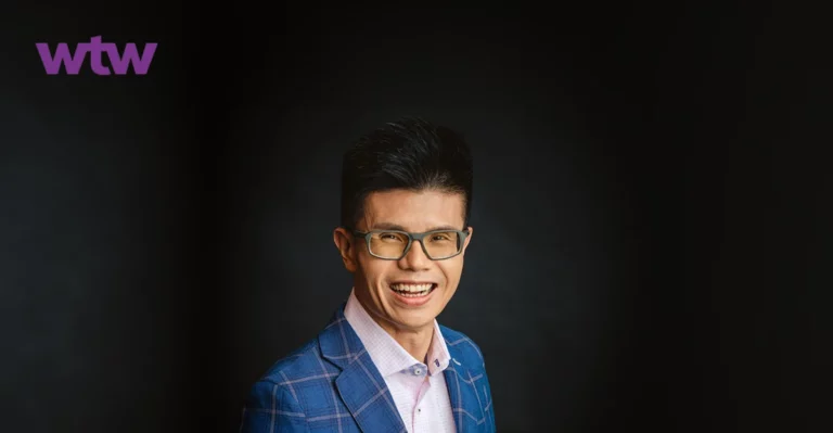 Drian Chua smiling in front of a black background.