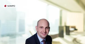 Alasdair Walker in suit and tie, smiling.