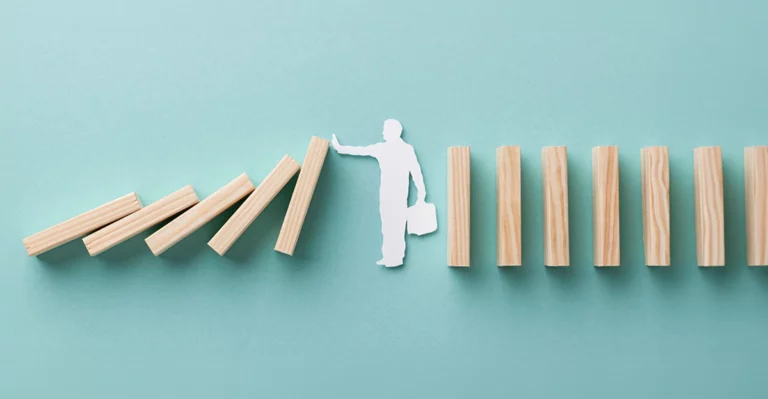 A man is standing on top of a stack of dominoes.