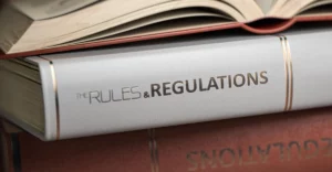 The rules and regulations book is stacked on top of another book.