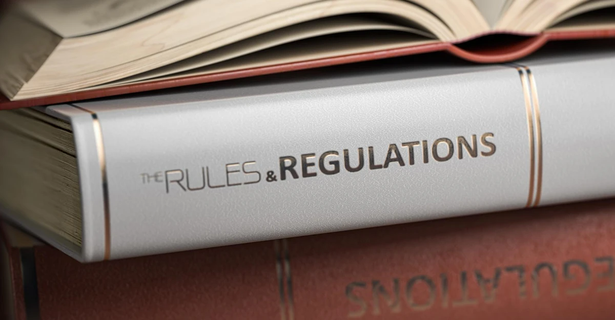The rules and regulations book is stacked on top of another book.