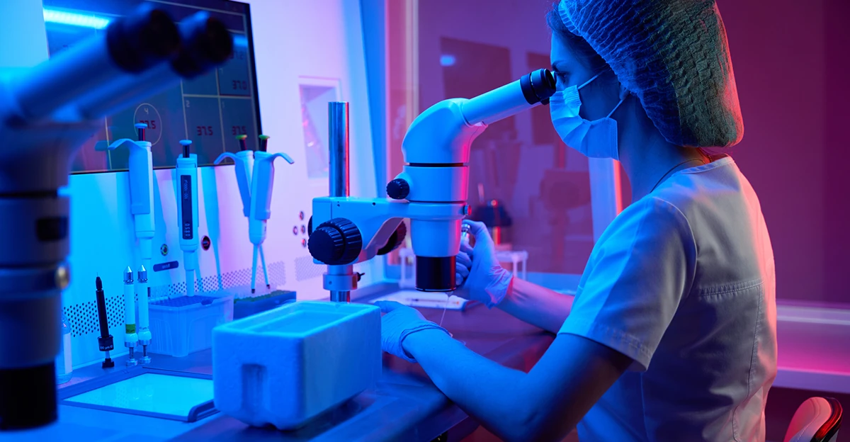 A woman is working with a microscope in a lab.