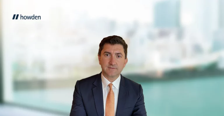 A man in a suit and tie is sitting in front of a background.