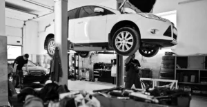 A black and white photo of a mechanic working on a car.