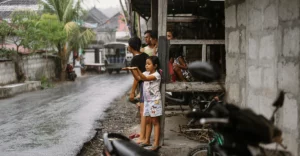 A group of people standing on a street in the rain.