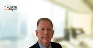 A man in a suit and tie is standing in front of a blurry background.