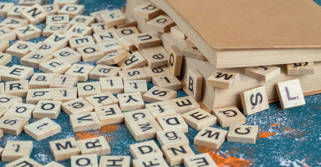 A stack of wooden scrabble letters on top of a book.