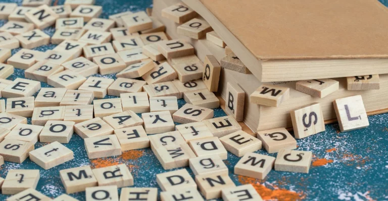 A stack of wooden scrabble letters on top of a book.