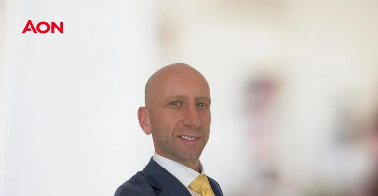 A bald man in a suit and tie is smiling.