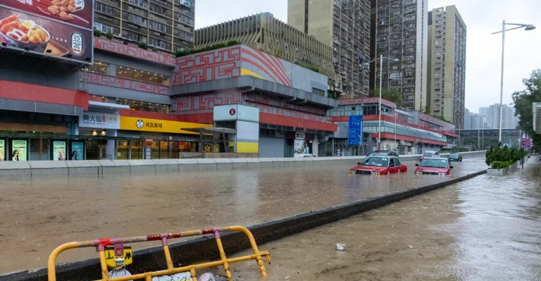 A flooded street with cars and buildings in the background.