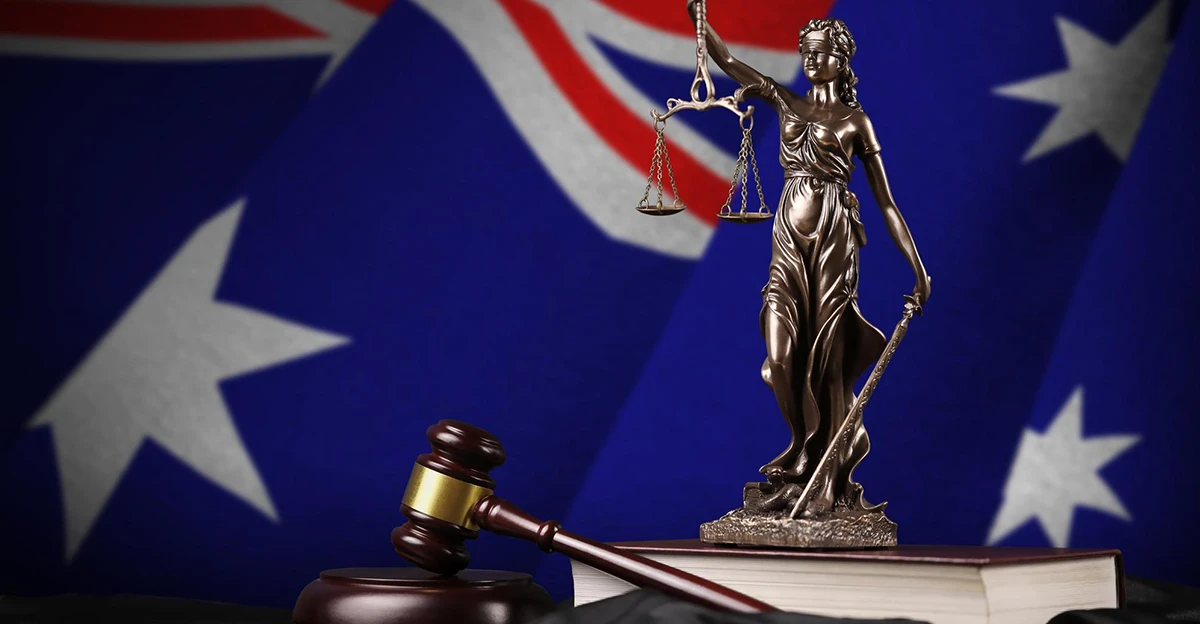 A statue of a judge with a gavel in front of an australian flag.