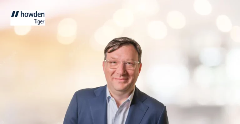 A man in a suit is standing in front of a blurry background.