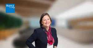 A woman in a business suit standing in front of a blurry background.