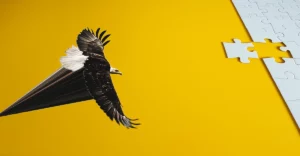 An eagle flies over a puzzle piece on a yellow background.