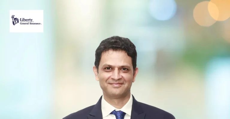 A man in a suit and tie is standing in front of a blurry background.