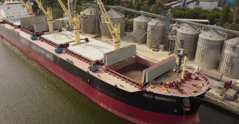 An aerial view of a large cargo ship docked in a river.