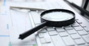 A magnifying glass sits on top of a keyboard.