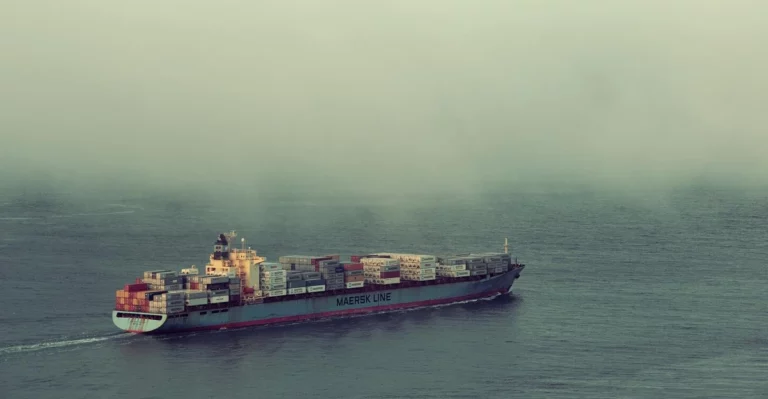 A container ship sailing in the ocean on a foggy day.