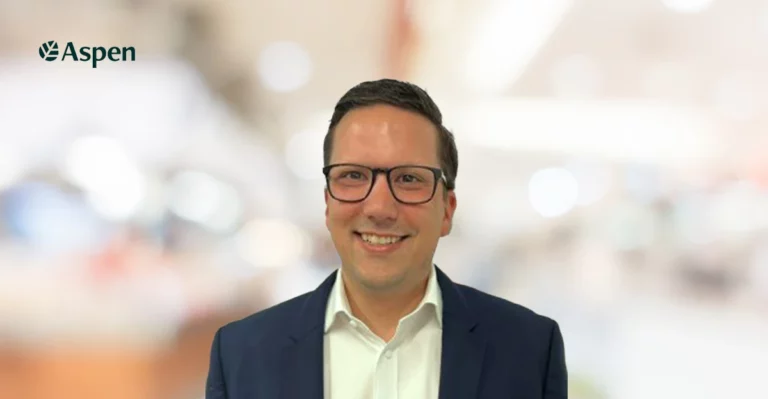 A man wearing glasses and a suit smiles for the camera.