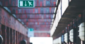 An exit sign hanging from a brick wall.