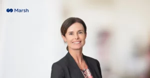 A woman in a business suit smiling in front of a wall.