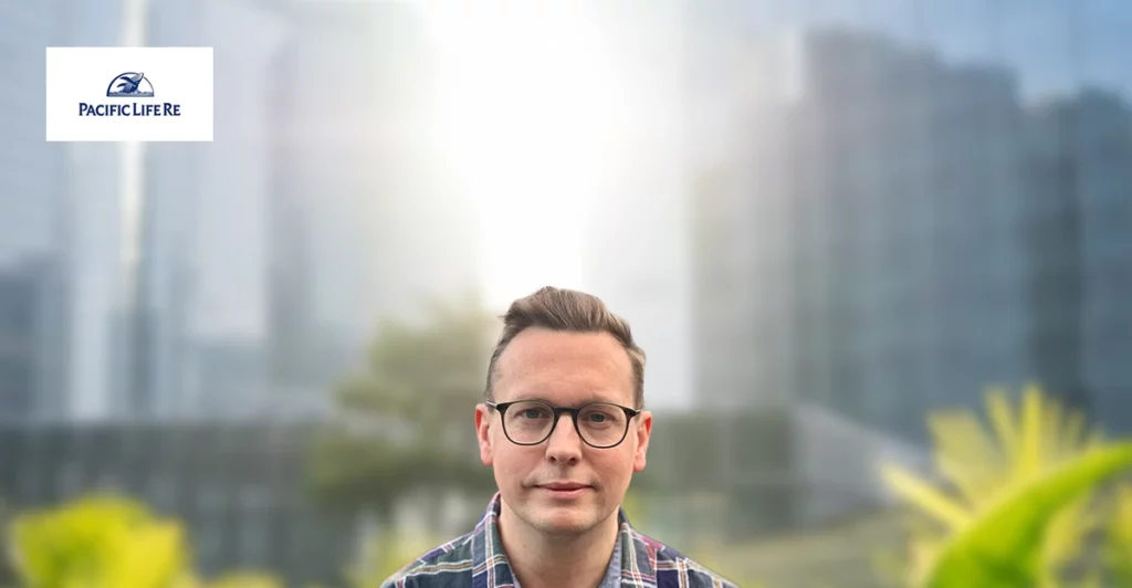 A man in glasses is standing in front of a building.