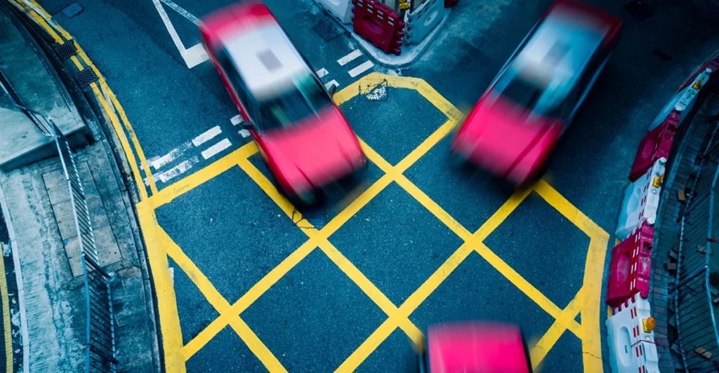 Red cars driving on a busy street in hong kong.