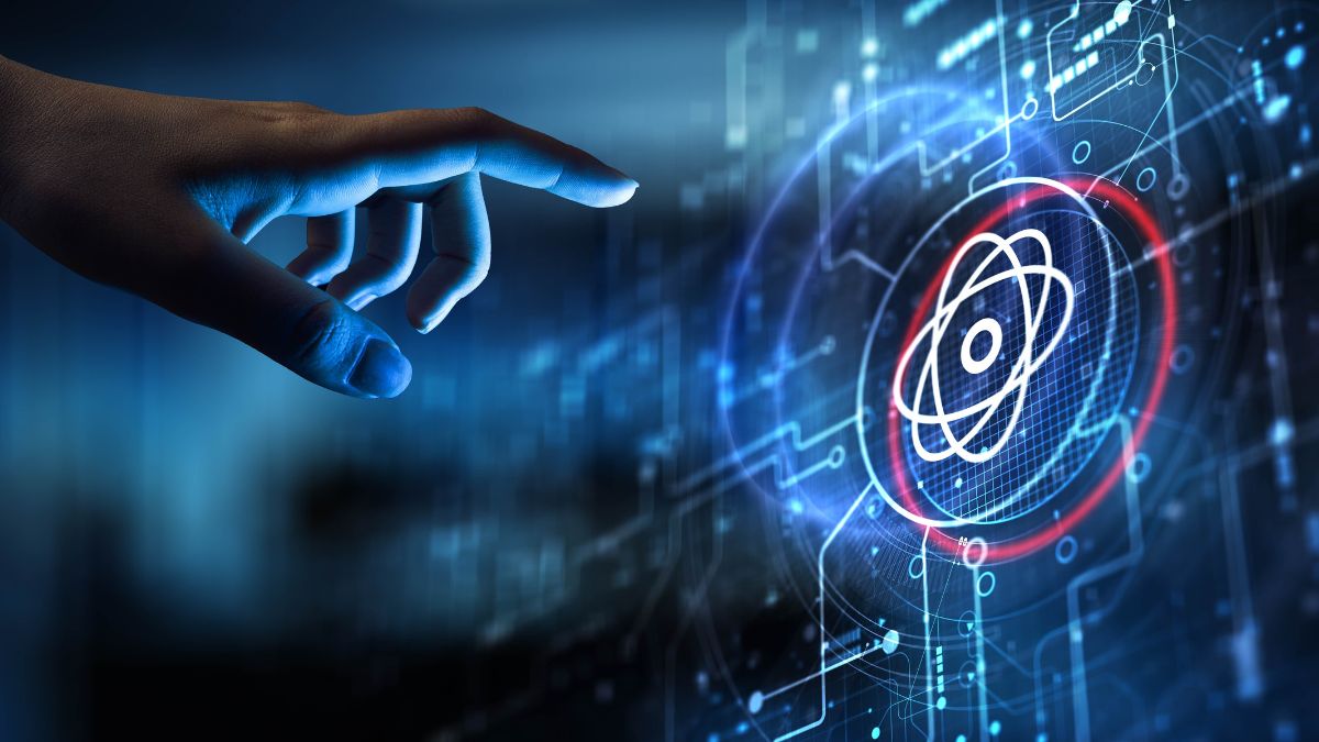 A hand extends toward a glowing holographic display with an atomic symbol, symbolizing futuristic science and technology.
