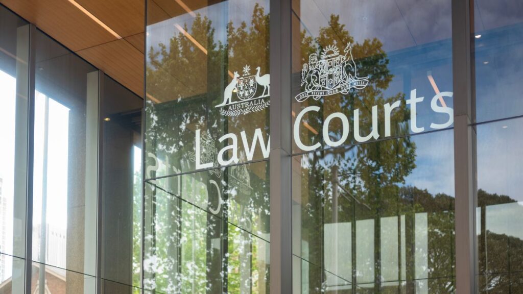 Exterior view of a courthouse entrance with glass panels displaying 'Law Courts' and government crests