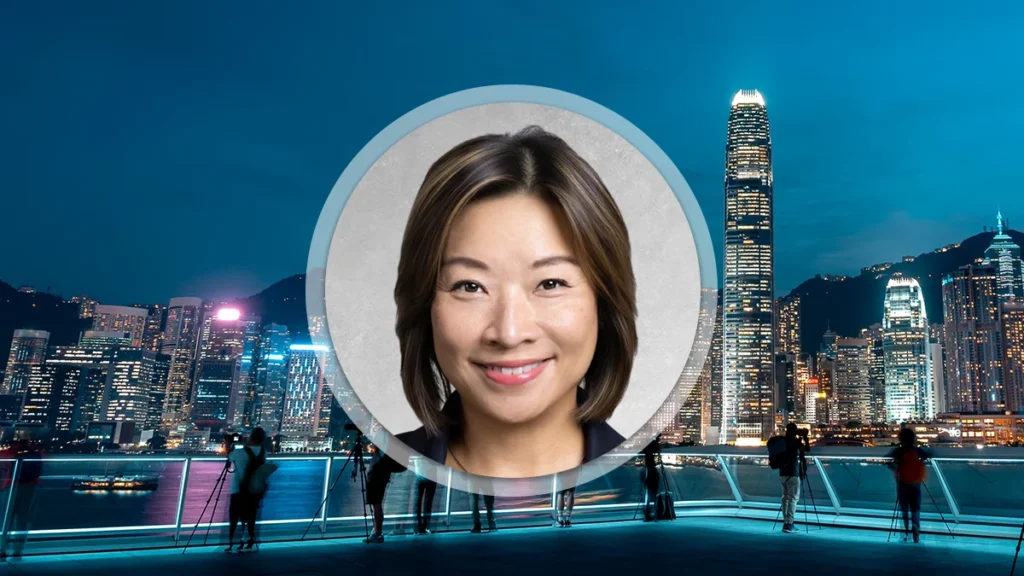 Smiling woman’s headshot inside a circular frame over a night city skyline.