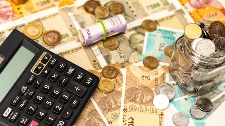 Calculator surrounded by banknotes and scattered coins with a jar of coins on the right, depicting budgeting or savings.