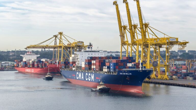 Large container ship CMA CGM loaded with colorful stacked cargo at a busy port with tall yellow gantry cranes nearby