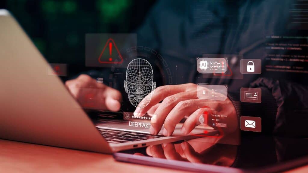 Hands typing on a laptop with floating security icons and a wireframe face, highlighting deepfake threats in cybersecurity contexts.
