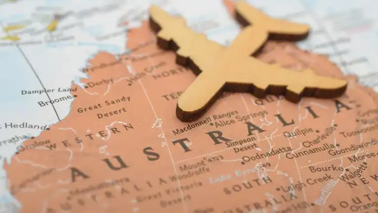 Wooden airplane figurine on a map of Australia, centered over Western Australia area.