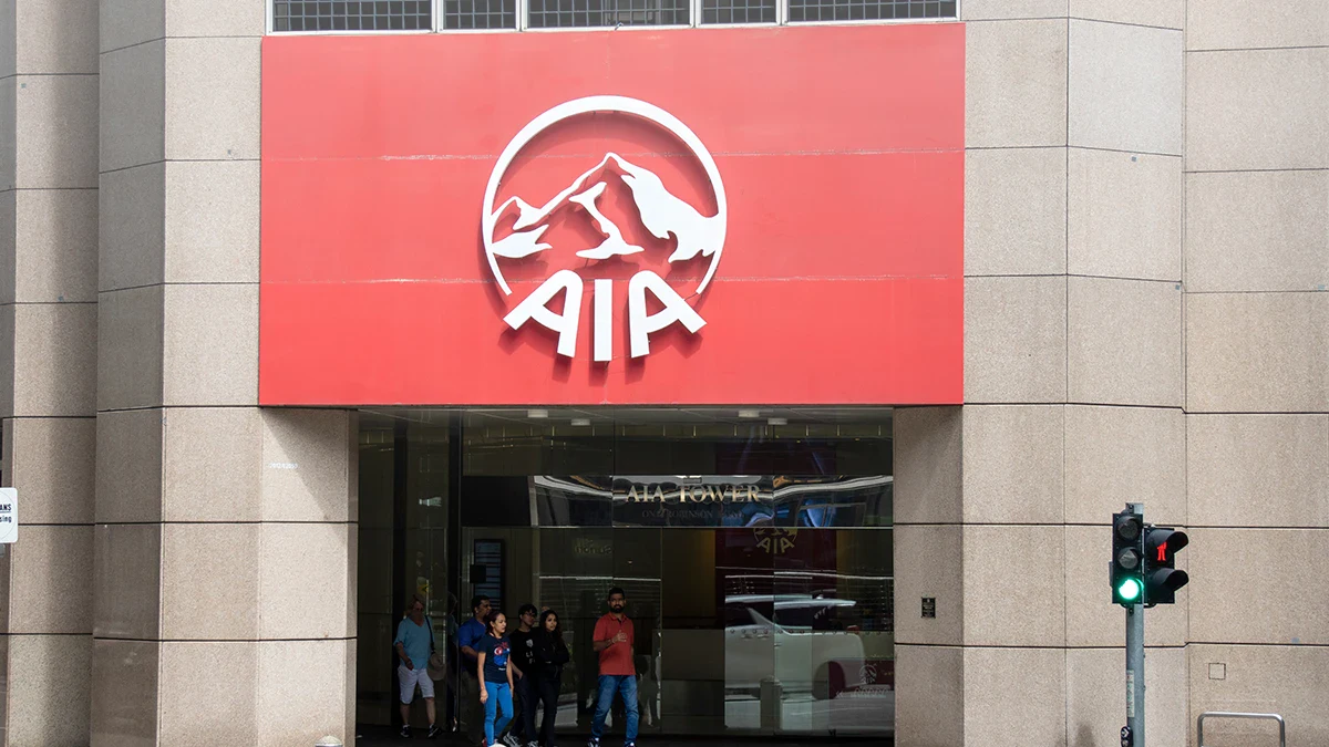 AIA office entrance with a red sign displaying the white AIA logo above glass doors and pedestrians entering