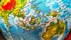 Close-up of a world globe focusing on Southeast Asia and Australia, with red travel routes drawn over the map.