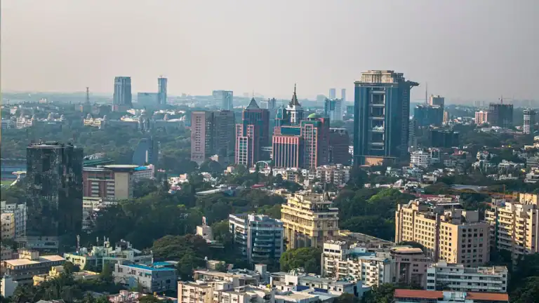 Panoramic city skyline with tall office towers and residential buildings surrounded by trees on a hazy day