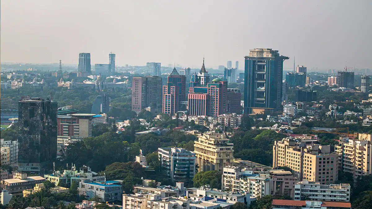 Panoramic city skyline with tall office towers and residential buildings surrounded by trees on a hazy day
