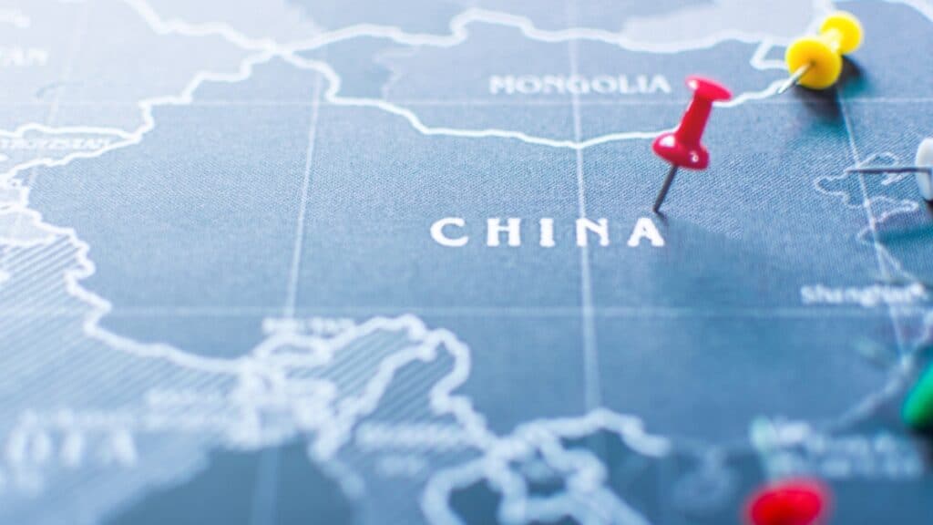 Close-up of a blue map showing China with colorful push pins marking locations in red, yellow, and green.