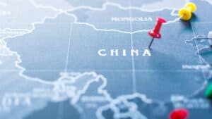 Close-up of a blue map showing China with colorful push pins marking locations in red, yellow, and green.