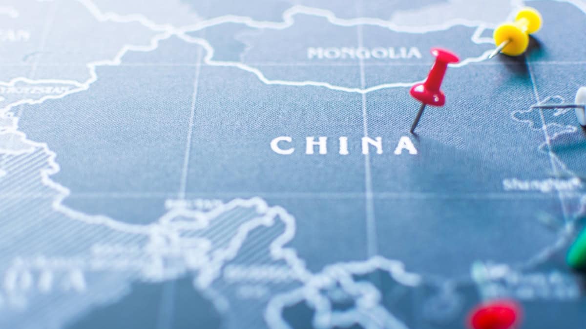 Close-up of a blue map showing China with colorful push pins marking locations in red, yellow, and green.