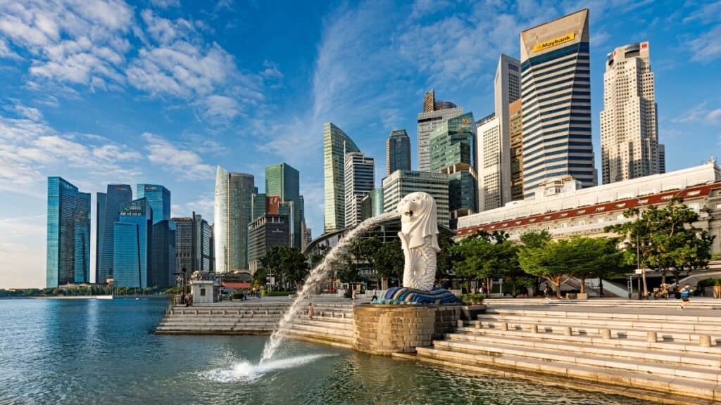 Merlion statue spouting water with Marina Bay skyline and blue sky in Singapore.