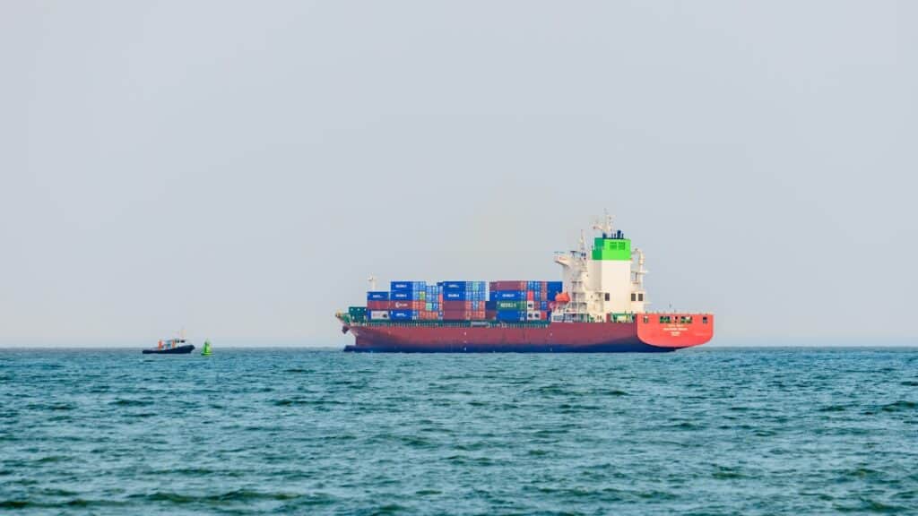 Large cargo ship navigating the Strait of Hormuz with containers onboard.