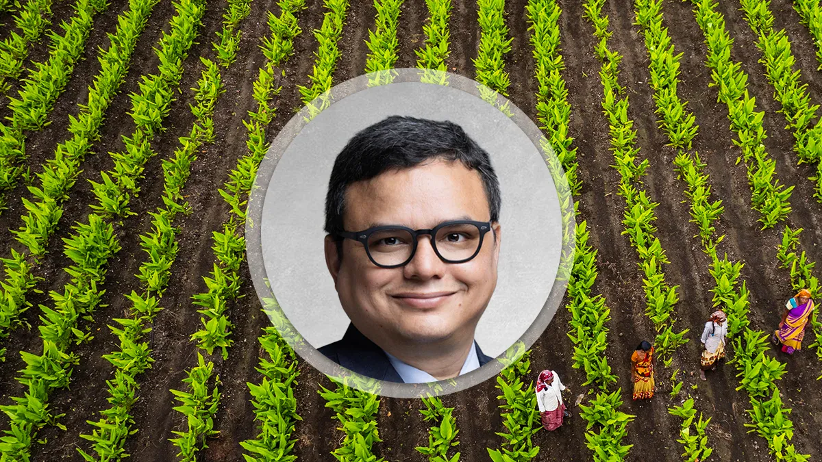 Aerial view of a farm with evenly spaced green crop rows and a circular portrait of a man wearing glasses centered over the field.